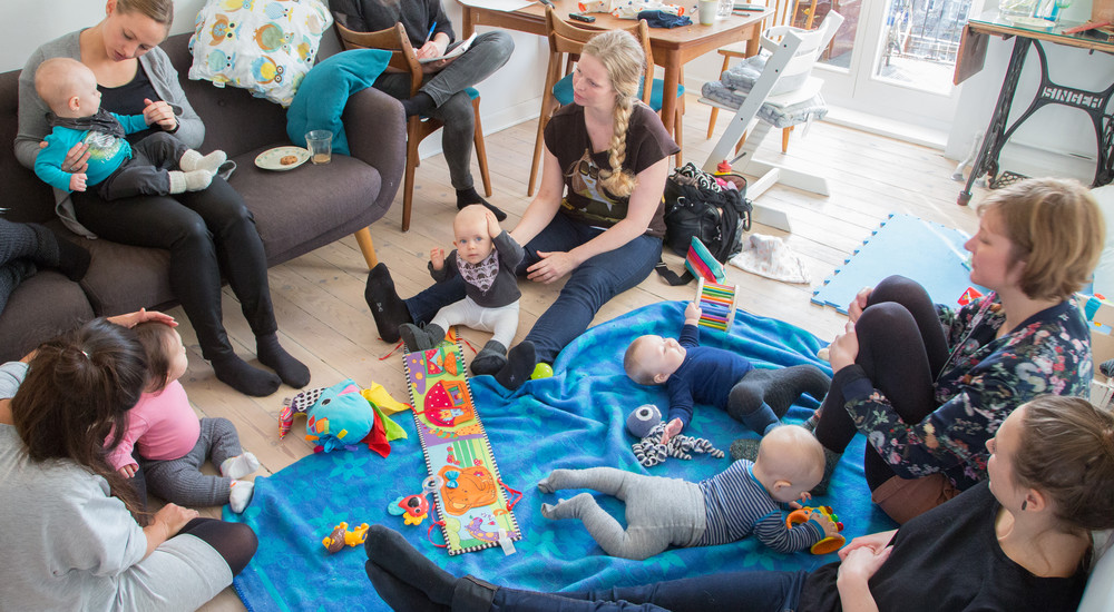 Mødregruppe sidder i en cirkel omkring deres små børn 
